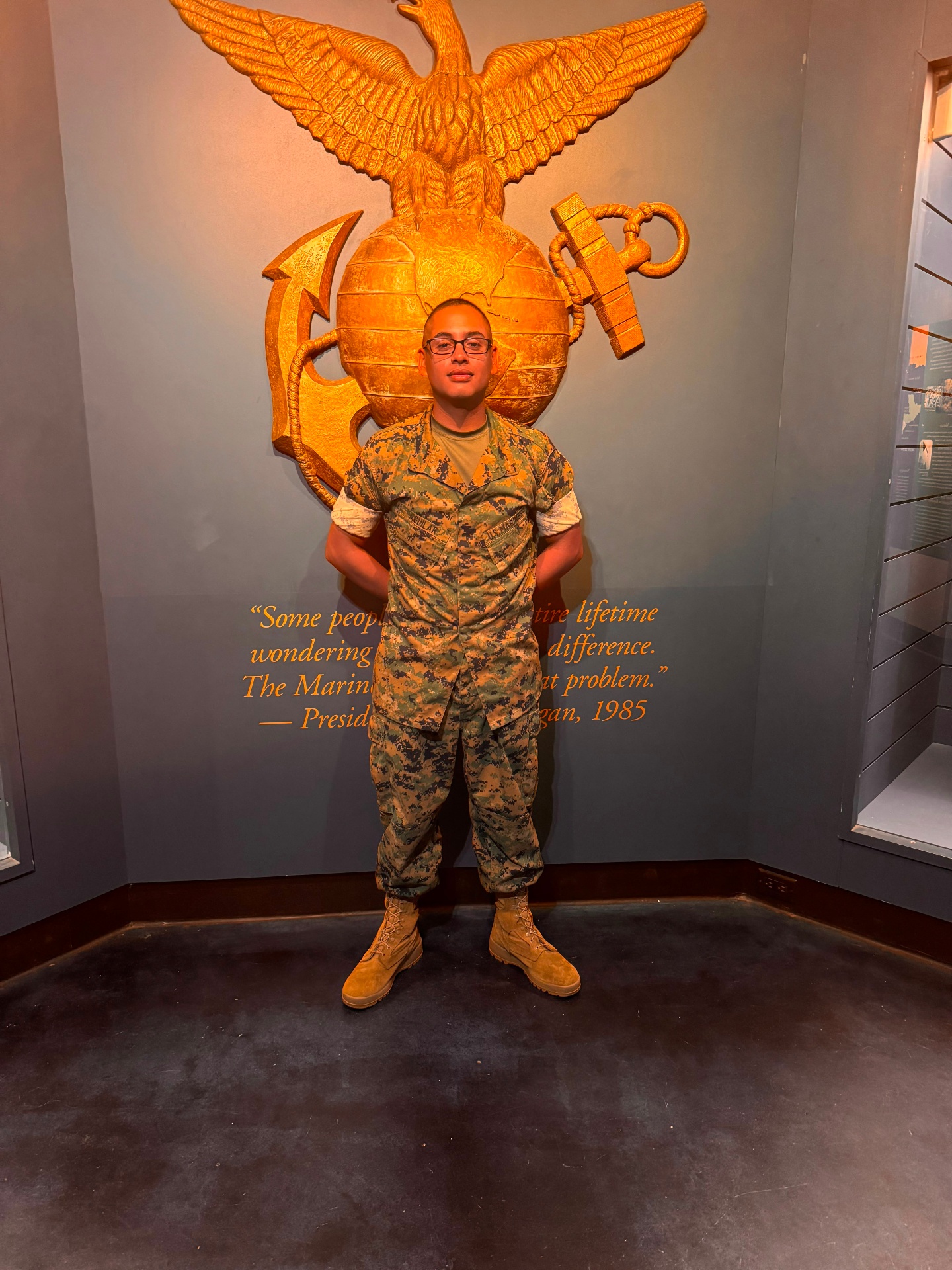 City Star family Marine standing at attention beneath the Eagle, Globe & Anchor — the discipline behind our DMV crews